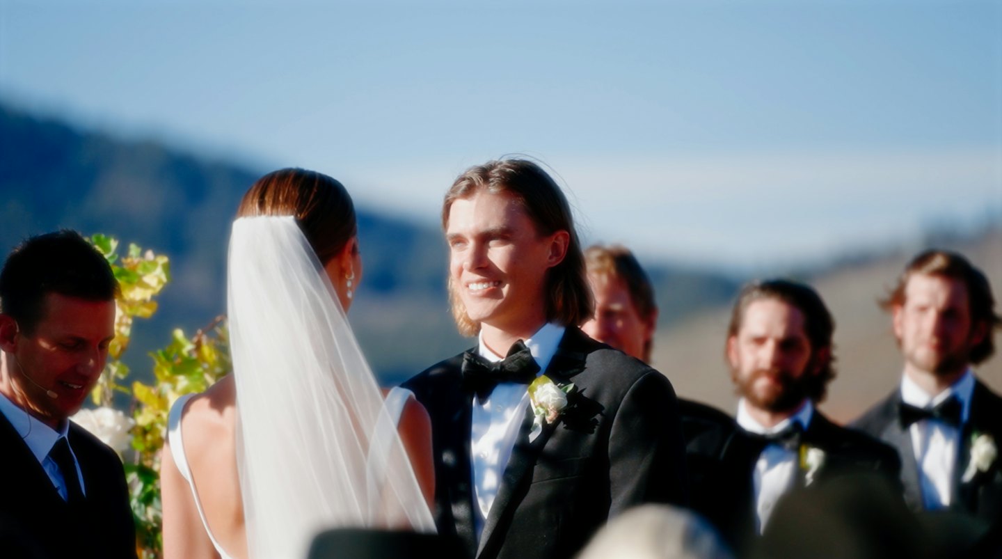 Groom smiles at his bride during their outdoor wedding ceremony.