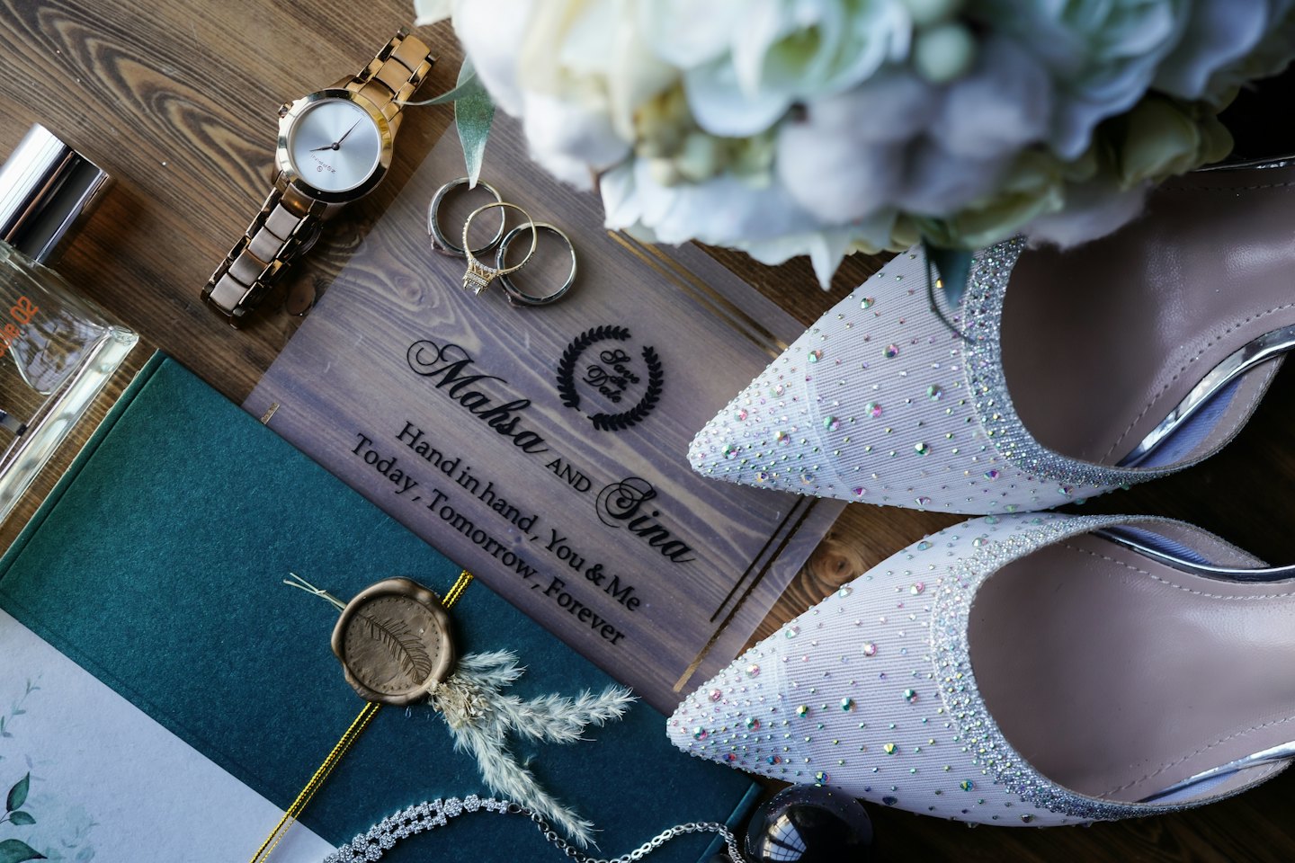 Wedding accessories and rings arranged on a wooden surface.